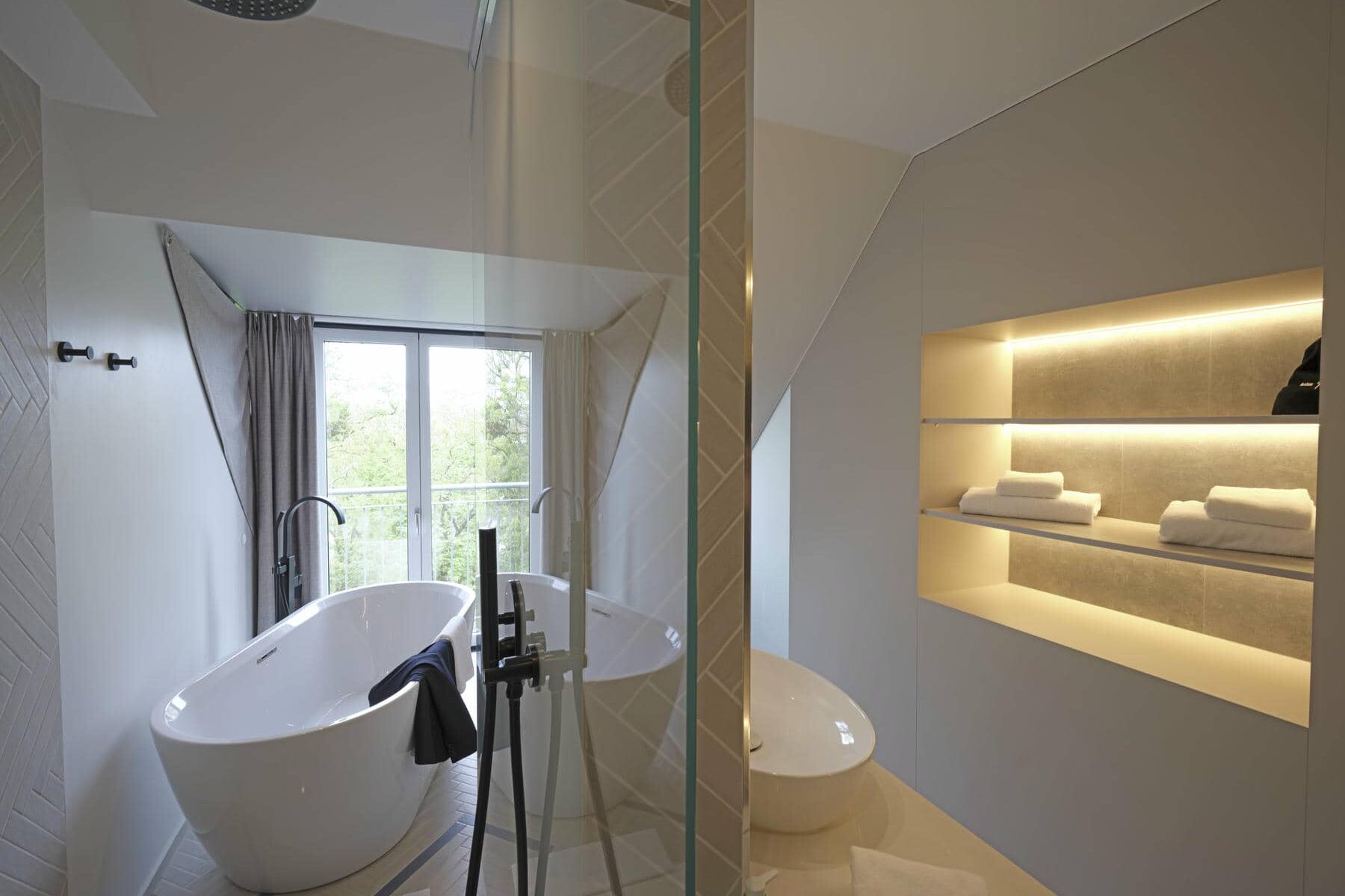 Modernes, lichtdurchflutetes Badezimmer in der Superior Suite im Novotel München City mit Regendusche und freistehender Badewanne mit Stadtblick