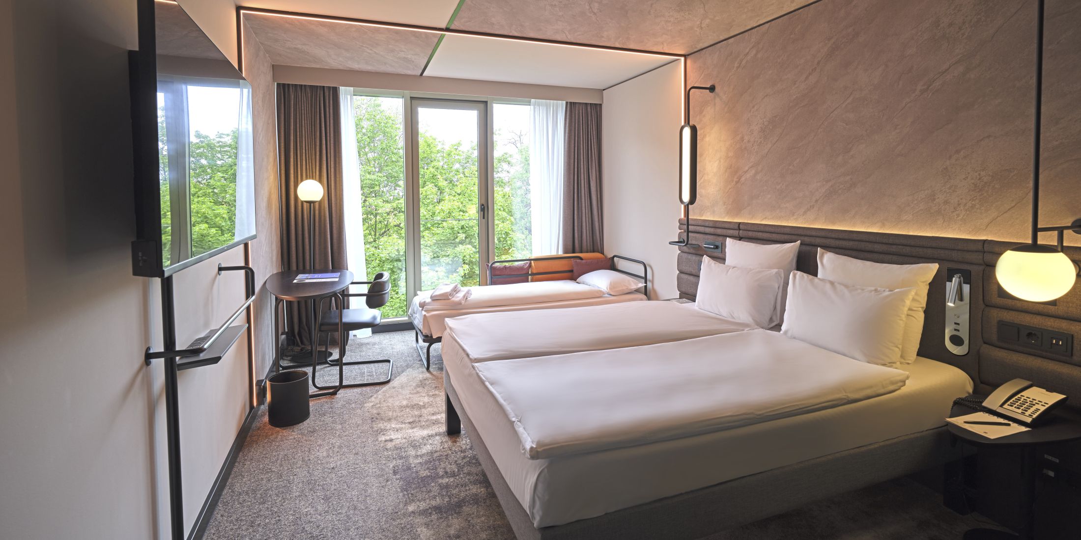 Premium Familienzimmer vorbereitet für 3 Personen im Novotel München City mit Kingsize-Bett, Schreibtisch, Schlafsofa, modernem Dekor und Blick auf die Stadt