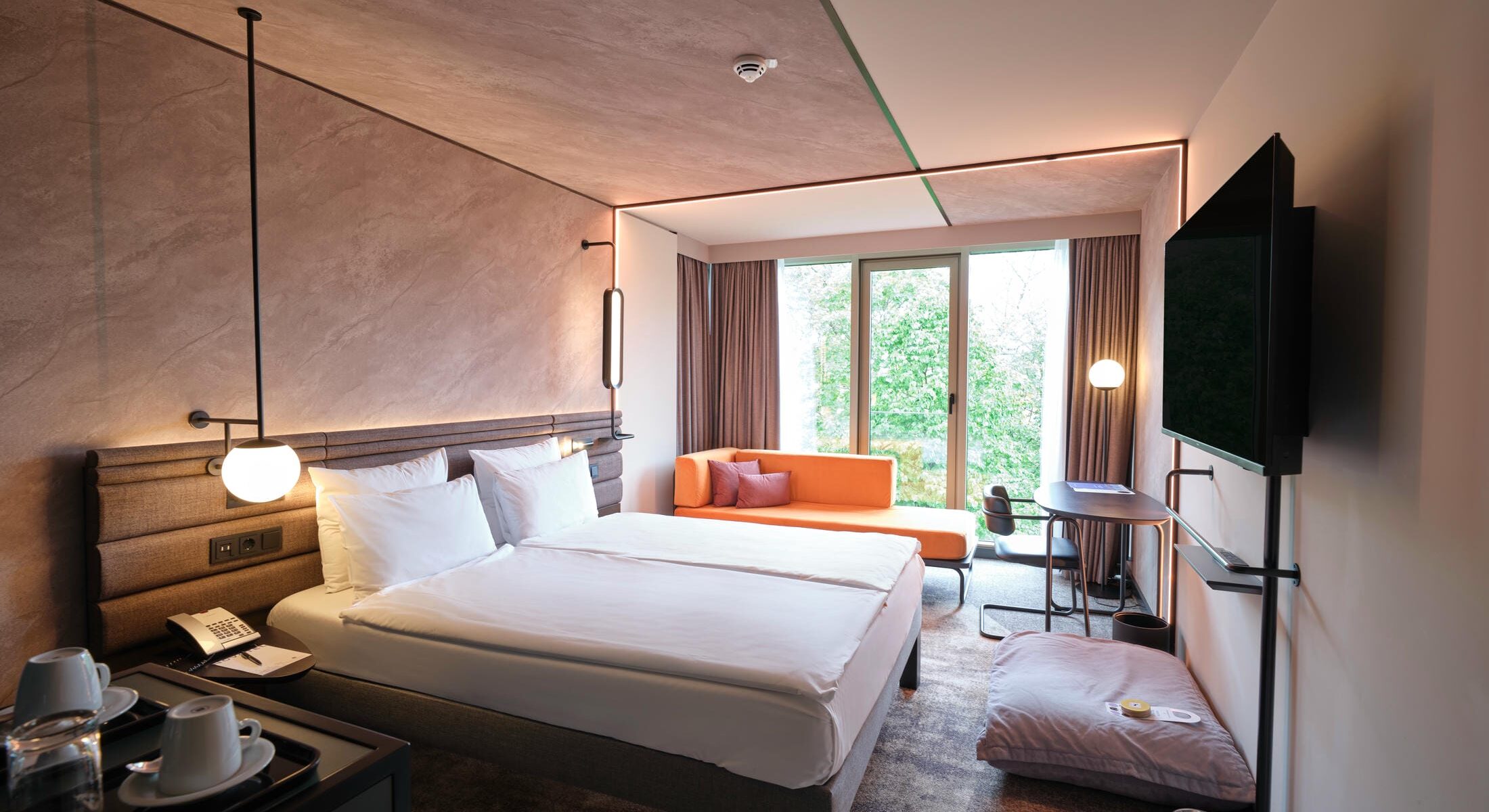 Premium Familienzimmer im Novotel München City mit Kingsize-Bett, Schreibtisch, Schlafsofa, Hundebett und Blick auf die Stadt