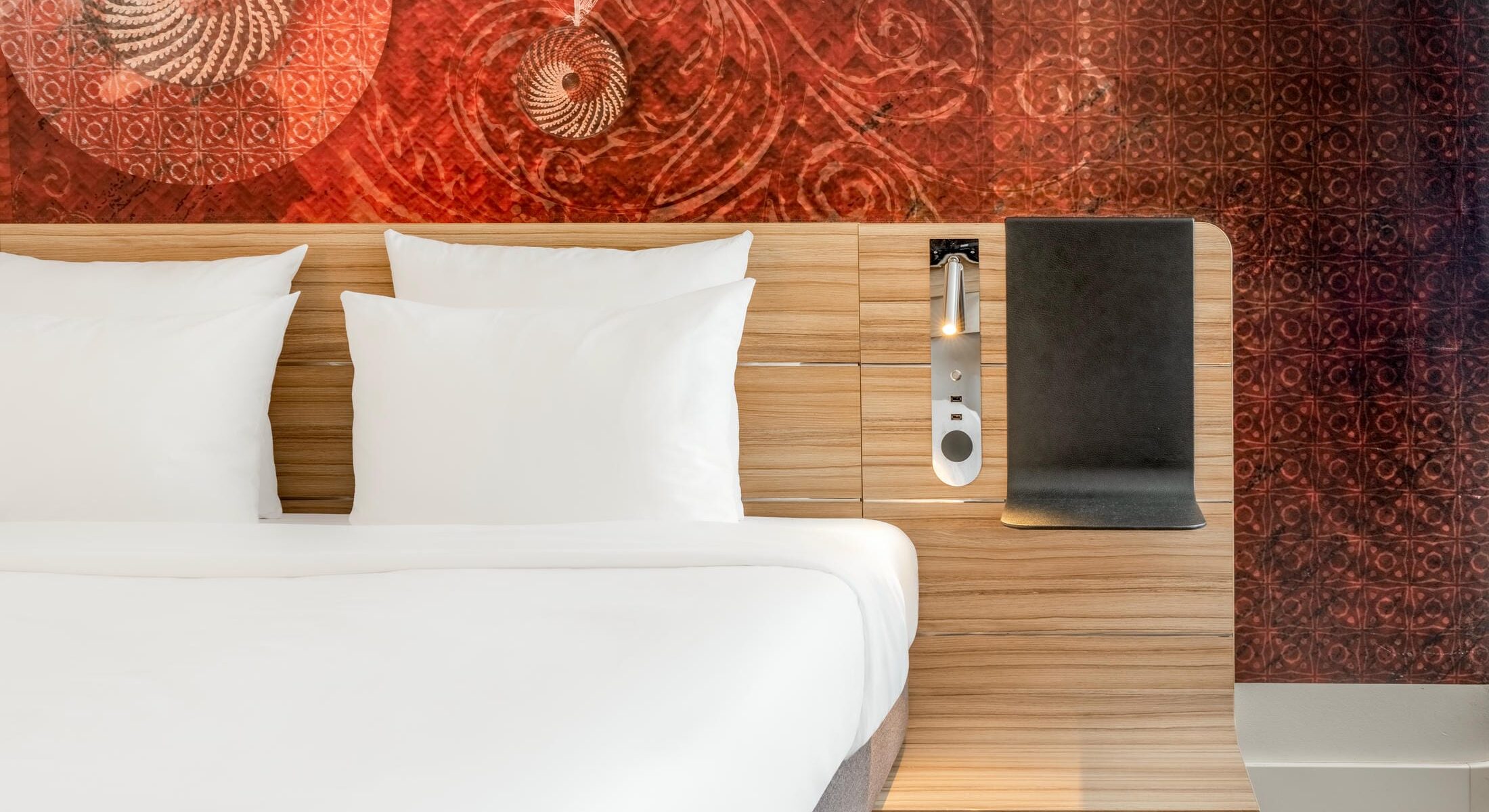Detailbild vom Bett mit Leselampe und Deko-Tapete im Superior Businesszimmer im Novotel München City