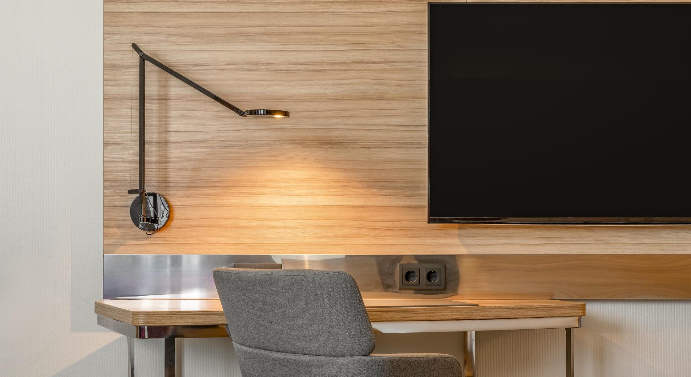 Schreibtisch mit Sessel und Schreibtischlampe sowie Flachbild.Fernseher im Novotel München City