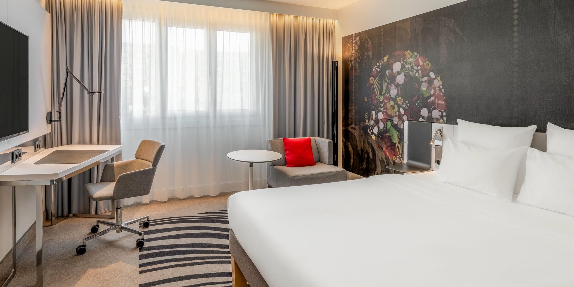Standard Doppelzimmer mit großem Doppelbett, Schreibtisch, Flachbild Fernseher und Sitzecke im Novotel München City